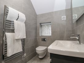 A bathroom with a wall-mounted toilet sink and a towel rack with white towels at The Groom's Cottage Goodmanham Wold near Market Weighton