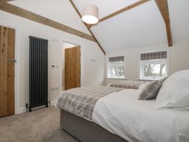 A bedroom with two single beds with plaid bedding a black radiator and wooden doors at The Groom's Cottage Goodmanham Wold near Market Weighton