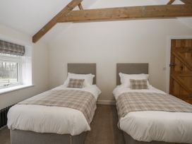 A bedroom with two single beds and checked bed runners near a window at The Groom's Cottage Goodmanham Wold near Market Weighton