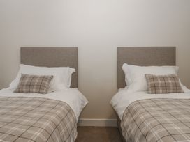 A bedroom with two single beds with brown plaid bedding and matching pillows at The Groom's Cottage in Goodmanham Wold near Market Weighton