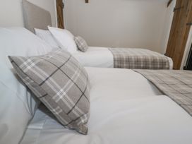 A bedroom with two single beds with plaid pillows and blankets at The Groom's Cottage Goodmanham Wold near Market Weighton