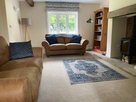 A living room with two brown sofas and a patterned rug near a window and a wood burning stove at The Groom's Cottage Goodmanham Wold near Market Weighton