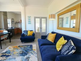 A living room with a blue sofa and open kitchen area at Little Orme View in Llandudno