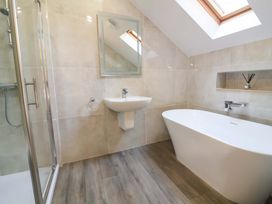 A bathroom with a shower, bathtub, sink, and mirror at The Linhay in Washford near Watchet