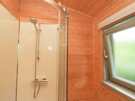 A shower with glass door and window at Elm Lodge in Ulverston