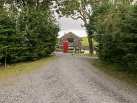 A gravel road leading to a stone building with a red telephone box at Elm Lodge in Ulverston