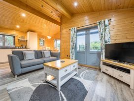 A living room with a sofa, coffee table, and TV at Elm Lodge in Ulverston