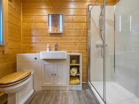 A bathroom with a shower, sink, and wood paneling at Elm Lodge in Ulverston