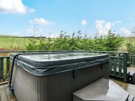 A hot tub on a deck surrounded by greenery at Elm Lodge in Ulverston