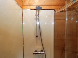 A shower with a wall and faucet at Elm Lodge in Ulverston