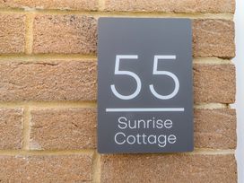 A house nameplate on a brick wall at Sunrise Cottage in Beadnell