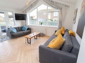 A living room with sofas and a television at Sunrise Cottage Beadnell