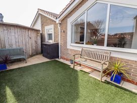 A garden with a bench and planter at Sunrise Cottage Beadnell