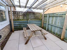 An outdoor area with a wooden table and benches at Sunrise Cottage in Beadnell