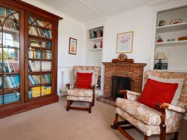 A living room with bookshelves and armchairs at Penrose Farm Cottage St Keverne