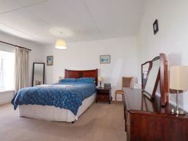 A bedroom with a bed and nightstand at Penrose Farm Cottage St Keverne