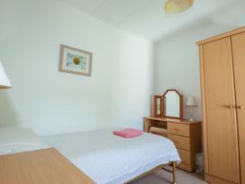 A bedroom with a bed and wardrobe at Penrose Farm Cottage in St Keverne
