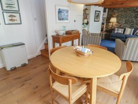 A dining room with a round table and framed pictures at Pegs in Porthleven