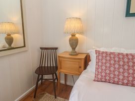 A bedroom corner with a lamp, chair, and nightstand at Pegs in Porthleven