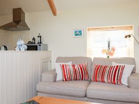 A living room with a sofa and kitchen appliances at Mithian Cottage in St Agnes