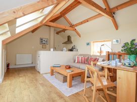 A living room with a sofa, coffee table, and dining area at Mithian Cottage in St Agnes