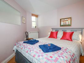 A bedroom with a bed and a chair at Mithian Cottage in St Agnes