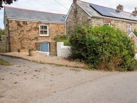 An outdoor view of a stone cottage with a gravel area and plants at Mithian Cottage, St Agnes