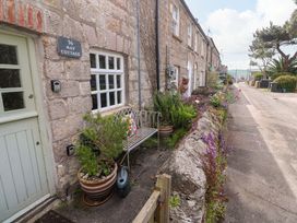 An outdoor view of May Cottage with a bench and flowers in Pentewan