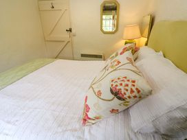 A bedroom with a bed and lamp at May Cottage in Pentewan