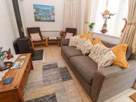 A living room with a sofa and wooden chairs at Godrevy Cottage in Hayle