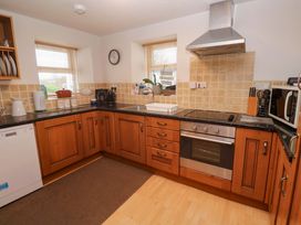 A kitchen with cabinets and appliances at Godrevy Cottage in Hayle