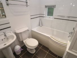 A bathroom with a shower over a bathtub and sink at Banneth in Helford