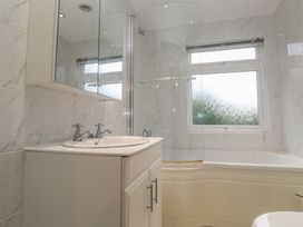A bathroom with a sink, mirror, shower, and bathtub at Banneth Helford