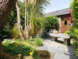 A garden with a stone bench and metal chairs at Trevenning Chapel Near Port Isaac