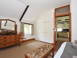 A bedroom with a dresser, mirror, and wardrobe at Trevenning Barn Near Port Isaac
