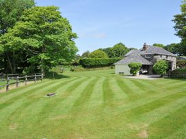 A garden with a house and trees at Trevenning Barn near Port Isaac