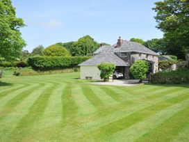 A house with a lawn and trees at Trevenning Barn Near Port Isaac