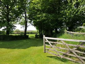 A garden with a wooden gate and trees at Trevenning Barn Near Port Isaac