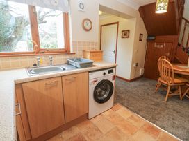 A kitchen with a washing machine and dining table at Two Hoots in Falmouth