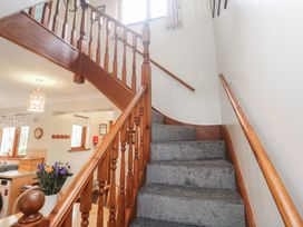 A stairway with wooden handrail and carpet at Two Hoots in Falmouth