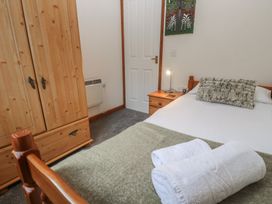 A bedroom with a bed, wardrobe, and decorative art at Two Hoots in Falmouth