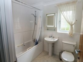 A bathroom with a bathtub, sink, toilet and window at Glebe House in Bigbury
