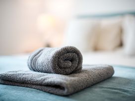 A towel rolled on a bed at Lanesend in St Agnes