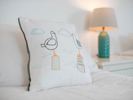 A pillow with bird design and lamp on a bedside table at Lanesend St Agnes