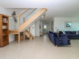 A living room with a staircase and bookshelves at Lanesend in St Agnes