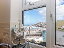 A kitchen window with mugs and a view of the sea at Blue Horizon in Brixham