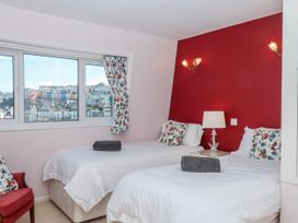 A bedroom with two beds and a window overlooking a colorful hillside at Blue Horizon in Brixham