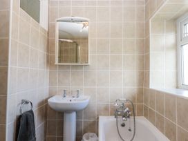 A bathroom with sink, mirror, and bathtub at Blue Horizon in Brixham