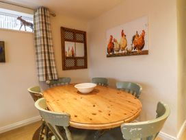 A dining room with a round wooden table and six chairs with a bowl on the table at The Old Hen Shed in Hainworth near Haworth