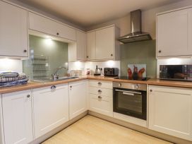 A kitchen with white cabinets wooden countertops a sink toaster kettle oven and microwave at The Old Hen Shed in Hainworth near Haworth